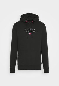 Sweat à capuche noir avec poche avant, cordons, texte "Tommy Hilfiger" et petit logo rouge, blanc et bleu sur la poitrine.