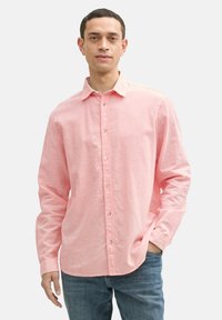 Lichtroze overhemd met knoopsluiting in een relaxte pasvorm, met een zachte textuur, lange mouwen en een klassieke kraag, gecombineerd met blauwe jeans.