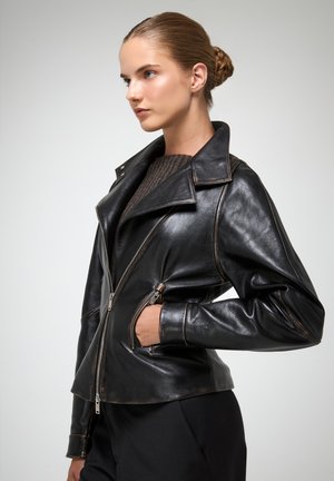 Zwarte leren motorjack met een gestructureerd ontwerp, decoratieve stiksels, een opstaande kraag en een asymmetrische rits.