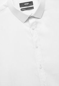 Witte, slim-fit, gecollarde shirt met een gestructureerde afwerking; heeft een knoopsluiting aan de voorkant en labels met merk en maat.