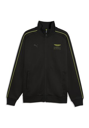Musta vetoketjullinen takki korkealla kauluksella, keltaiset reunukset hihoissa, Puma-logo vasemmassa rinnassa ja Aramco Formula One Team -embleemi oikeassa rinnassa.