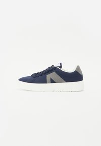 Zapatillas de malla azul marino con suela de goma blanca, punta redonda, parte superior texturizada y detalles en gris en los lados y la parte trasera. Diseño con cordones.