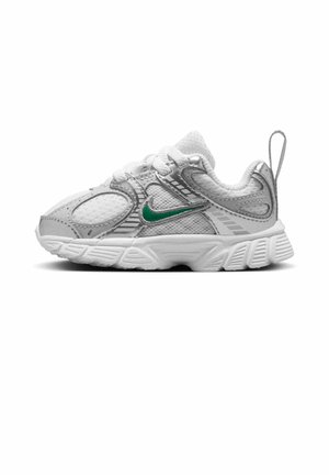 Białe i szare dziecięce tenisówki z zielonym logo Nike, panelami z siateczki, teksturowaną podeszwą, sznurowadłami i pętelką na pięcie, widoczne z boku.