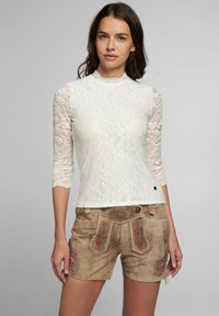Weißes Spitzenoberteil mit drei Viertelärmeln, hohem Ausschnitt und taillierter Passform, kombiniert mit braunen Shorts mit Blumenstickerei und Seitentaschen.