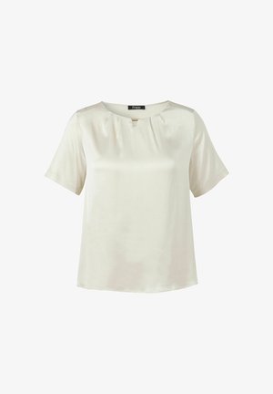 Blouse à manches courtes couleur crème avec encolure ronde, plis subtils et un petit détail en barre dorée sous le col, présentée sur fond blanc.
