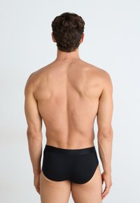 Caleçons pour hommes noirs vus de dos, avec une texture lisse et une taille élastique, sur un fond blanc uni.