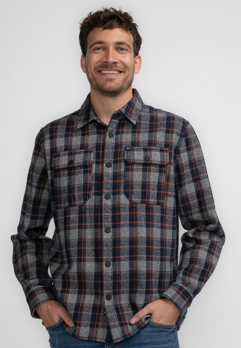 Gezellige ruitjesflannel overhemd in marineblauw, grijs en oranje. Beschikt over twee borstzakken, knoopsluiting en lange mouwen. Zachte textuur en relaxte pasvorm.