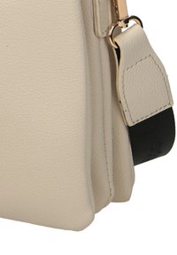 Borsa a tracolla in pelle beige con superficie texturizzata, hardware dorato e tracolla nera regolabile. Forma compatta e strutturata con accenti minimali.