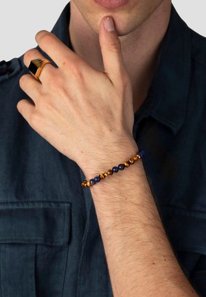 Perlenarmband mit abwechselnden braunen Tigeraugensteinen und marineblauen Steinen, ergänzt durch kleine, glänzende Metallakzente. Glatte Oberfläche, elastisches Band.