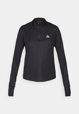 Μαύρο τοπ με μακριά μανίκια, ζιβάγκο γιακά και φερμουάρ μέχρι τη μέση, με υφή υφάσματος και λευκό λογότυπο στο αριστερό στήθος.