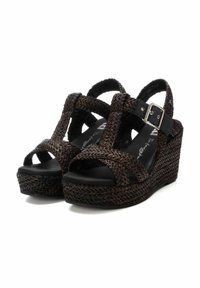 Sandalias de cuña con parte superior de textil trenzado negro y diseño de punta abierta. Cuenta con una correa ajustable en el tobillo con una hebilla metálica. Suela texturizada.