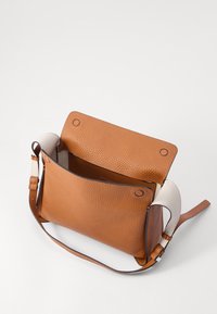 Borsa in pelle marrone chiaro con finitura testurizzata, dotata di chiusura a patta, tracolla regolabile e un accento di colore chiaro in contrasto sul lato.