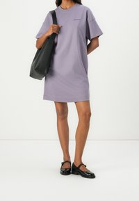 Levandulové bavlněné tričkové šaty s krátkými rukávy, kulatým výstřihem a jemným logem. Vykouzlily jsme je s černou taškou přes rameno a černými botami.