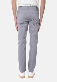 Pantaloni in cotone grigi con vestibilità dritta, dotati di tasche posteriori e texture liscia, abbinati a sneakers bianche su uno sfondo semplice.