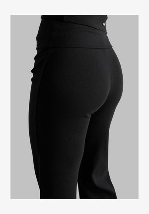 Leggings noirs côtelés avec une taille haute, une coupe moulante et une texture lisse. Comprend un détail matériel subtil sur la taille.