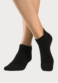 Black ankle socks made from a soft, stretchy material. Ribbed texture at the cuff. Low-cut design, exposing the ankle.