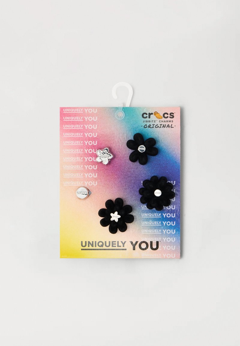 Sorte blomsterformede smykker med hvite aksenter på et regnbuegradientkort, med teksten "Unikt Deg" og sølvdekorer.