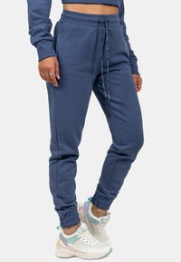 Marineblauwe joggerbroeken van zachte stof met eenkoordtaille, boorden aan de enkels en zijzakken, gecombineerd met meerkleurige sneakers.
