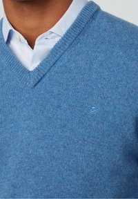 Pull bleu tricoté avec un col en V, doté d'un fin bord-côte au niveau de l'encolure. Logo discret brodé sur la poitrine dans une nuance de bleu assortie.