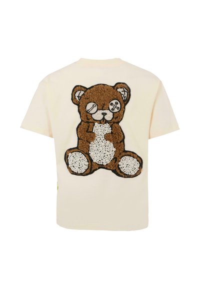 Crème-kleurig t-shirt met een pluchen teddybeer ontwerp in bruin en wit, met zwarte omlijning en speelse details op het gezicht van de beer.
