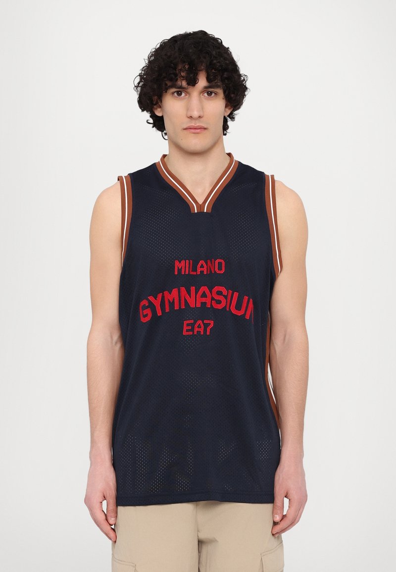 Modrý basketbalový dres s červeným nápisem "MILANO GYMNASIUM" a "EA7". Bez rukávů, design ve tvaru písmene V, vyrobený z prodyšné síťoviny.