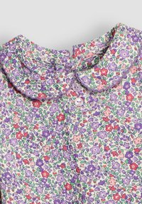 Gėlėmis raštuotas bliusonas su apvalia apykakle, kuriame dominuoja violetinės, rožinės ir žalios spalvos. Apykaklėje yra du mygtukai. Minkšta tekstūra.