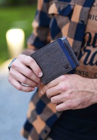 Gray fabric wallet with a blue accent. Features a slim design, rectangular shape, and textured surface. Held in a person's hand.