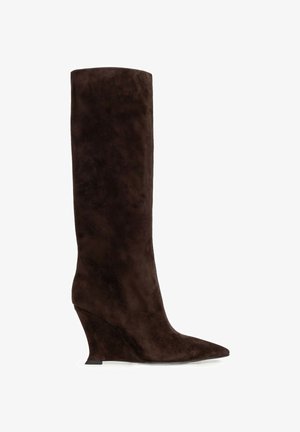 Bota hasta la rodilla de ante marrón oscuro con puntera puntiaguda y tacón cuña inclinado, presentada sobre fondo blanco.