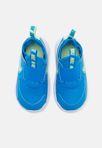 Baskets Nike bleues avec une tige en mesh, une sangle ajustable, un col rembourré et une semelle en caoutchouc blanche. Présente un accent vert sur la languette.