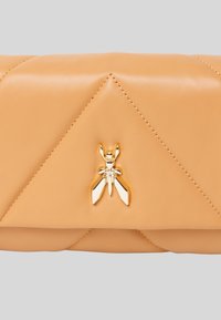 Clutch in pelle beige con design a rombi obliquo, dotato di una chiusura a forma di insetto dorato al centro. Texture liscia, stile minimalista.