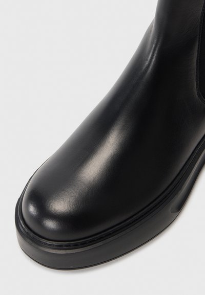 Svart läderankelstövel med rund tå, slät yta, minimalistisk design och en robust gummisula med en lätt upphöjning.