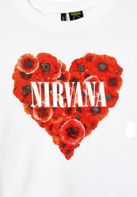 T-shirt bianco con un design a forma di cuore realizzato con papaveri rossi e una sovrapposizione centrale del testo "NIRVANA" in bianco e nero.