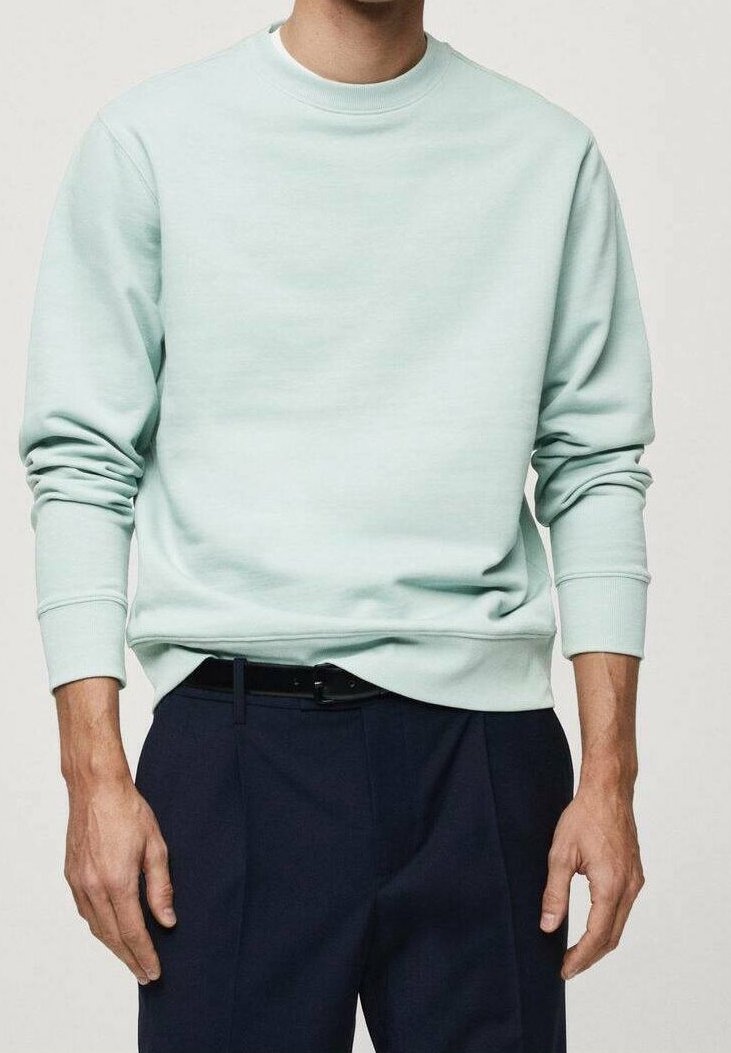 Helles mintgrünes Sweatshirt aus weichem Material mit Rundhalsausschnitt und gerippten Bündchen, kombiniert mit dunklen Hosen und einem sichtbaren schwarzen Gürtel.