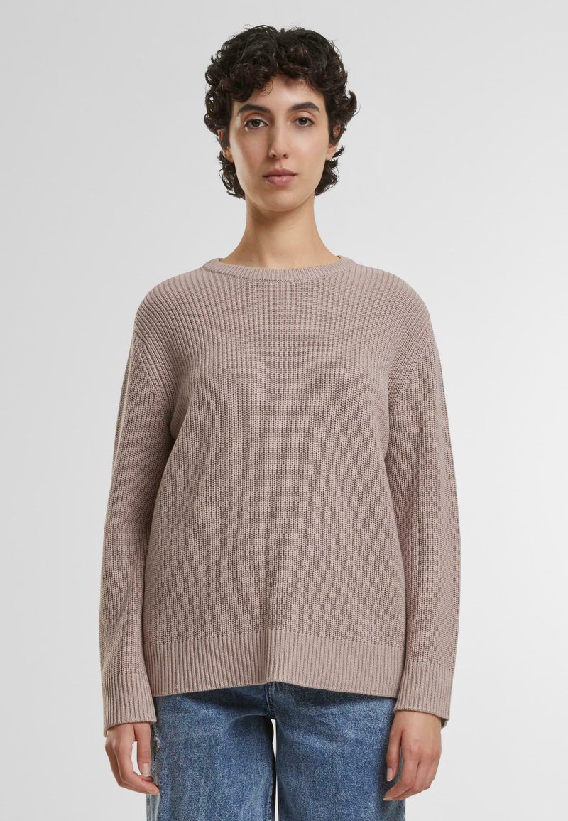 Beige teksturert strikket genser med ribbestrikket design, bred halslinje og lange ermer, kombinert med lyseblå denimjeans.