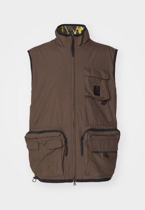 Gilet isolato marrone con colletto alto, zip frontale, due ampie tasche con zip e una piccola tasca con patta. L'interno presenta un motivo giallo.