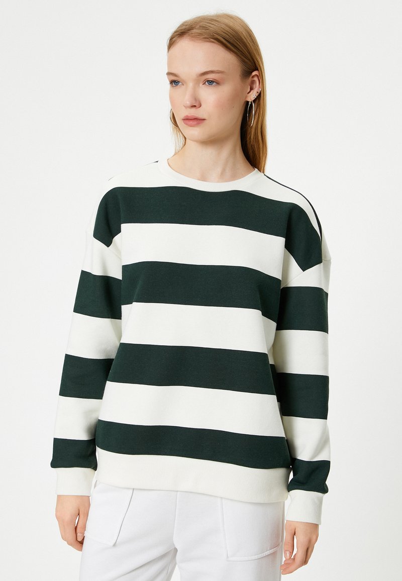 Felpa a righe verdi e bianche con maniche lunghe, colletto rotondo e polsini a costine. Realizzata in un tessuto morbido, presenta una vestibilità comoda.