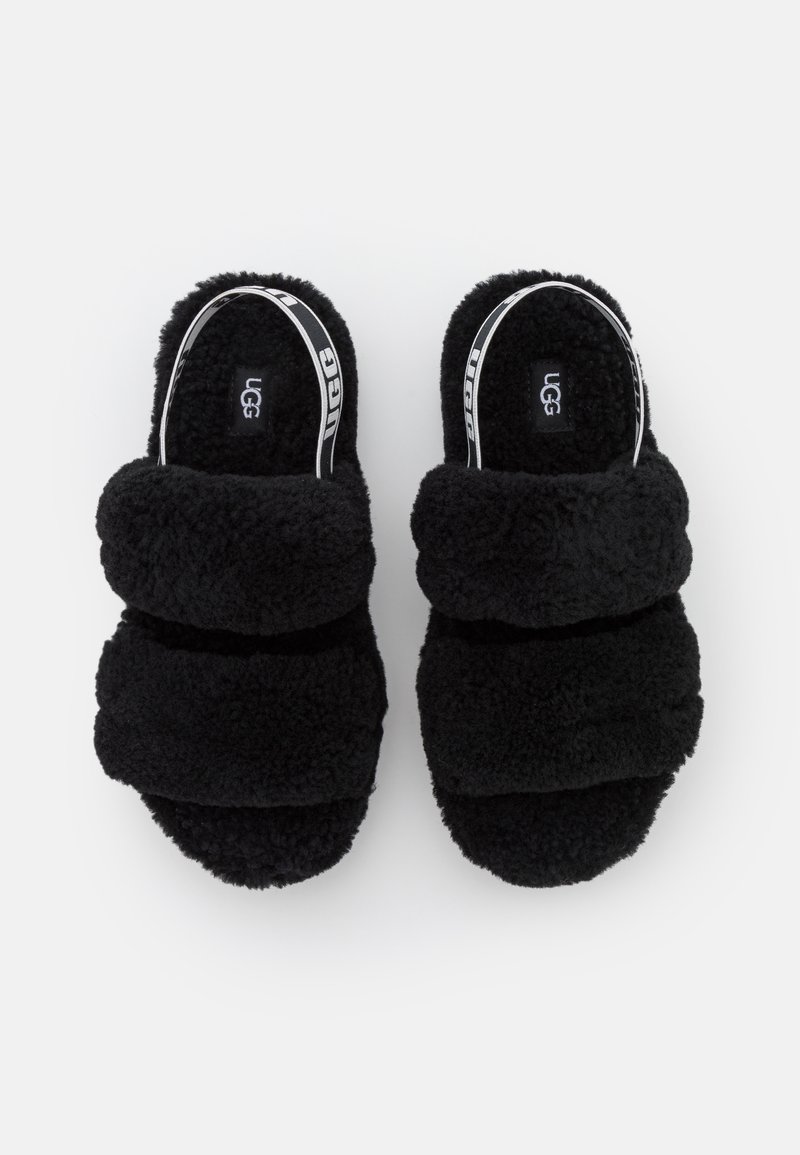 Chanclas de slide negras y esponjosas que presentan tres tiras anchas texturizadas con un acabado suave y un logo de marca en la plantilla.