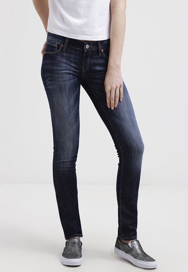 Tajta jeans i mörkblå denim, med en klassisk fem-fickdesign och lätt blekning. Matchas med metalliska slip-on skor.