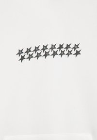 Fehér pulóver fekete csillagok grafikai ábrázolásával és a "STARS IN MOTION" felirattal, amely vízszintesen helyezkedik el a mellkas területén.