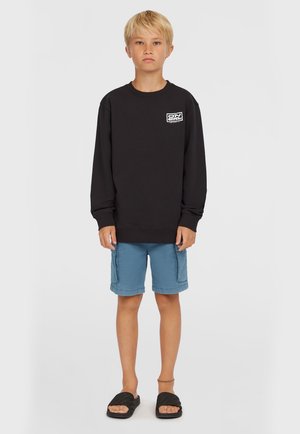 Zwarte sweatshirt met lange mouwen en een ronde hals, gecombineerd met blauwe shorts en zwarte slippers. Heeft een logo aan de voorkant.