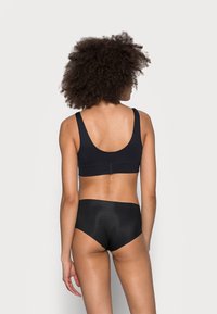 Zwarte bralette met brede bandjes en een naadloos ontwerp, gecombineerd met bijpassende high-waisted slips, beide gemaakt van gladde, zachte stof.