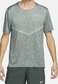 Camiseta deportiva de manga corta de Nike en tejido verde jaspeado. Presenta un escote redondo, un sutil patrón de chevron y acentos reflectantes.