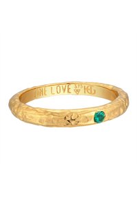 Guldfärgad ring med hamrad yta, inuti graverad med "ONE LOVE" och med en liten grön ädelsten som accent.