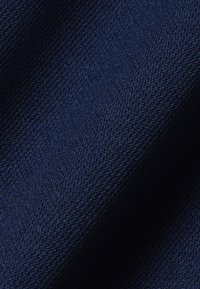Tissu bleu foncé avec un motif finement texturé, semblable à un tricot, et des plis subtils créant des ombres et des reflets doux.