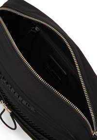 Borsa in tessuto nero con una superficie liscia, zip argentata, tasca interna con zip e dettagli in rete testurizzata. Design minimale con dettaglio del logo.