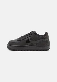Musta matalakotiminen Nike Air Force 1 -tenniskenkä, jossa on nahkainen päällinen, kiiltävä musta swoosh, kohotettu pohja ja "AIR" -merkintä kantapäällä.