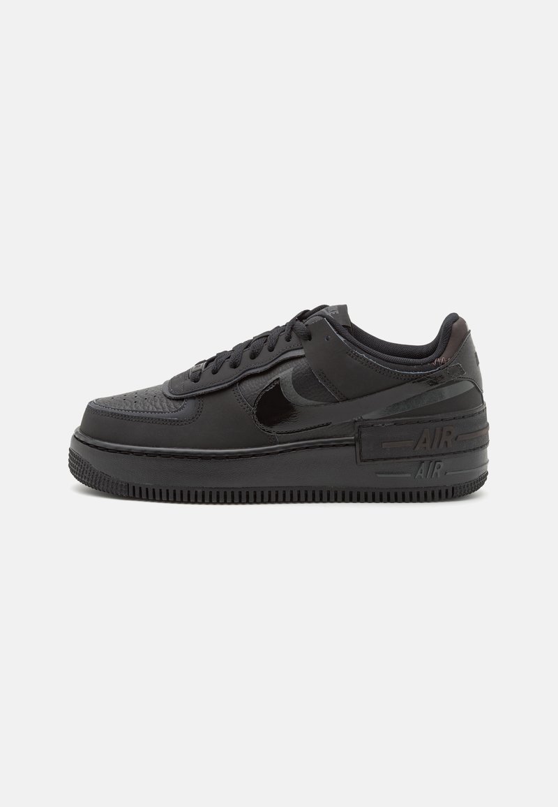 Musta matalakotiminen Nike Air Force 1 -tenniskenkä, jossa on nahkainen päällinen, kiiltävä musta swoosh, kohotettu pohja ja "AIR" -merkintä kantapäällä.