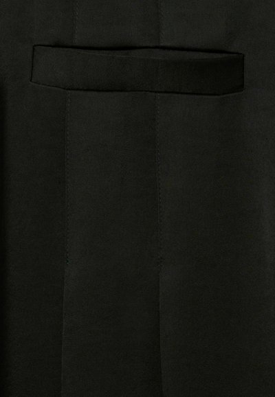 Tissu noir avec une finition texturée, présentant une grande poche et des coutures soigneusement cousues. Le matériau semble doux et lisse.