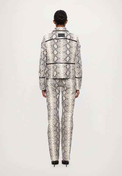 Chaqueta a medida con estampado de serpiente y pantalones a juego; textura metálica; patrón de pitón; acentos negros a lo largo de las costuras; modelo de espaldas.