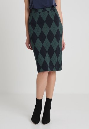 Jupe crayon argyle vert et marine avec une texture lisse, coupée à mi-longueur, taille haute, et associée à des bottines noires.